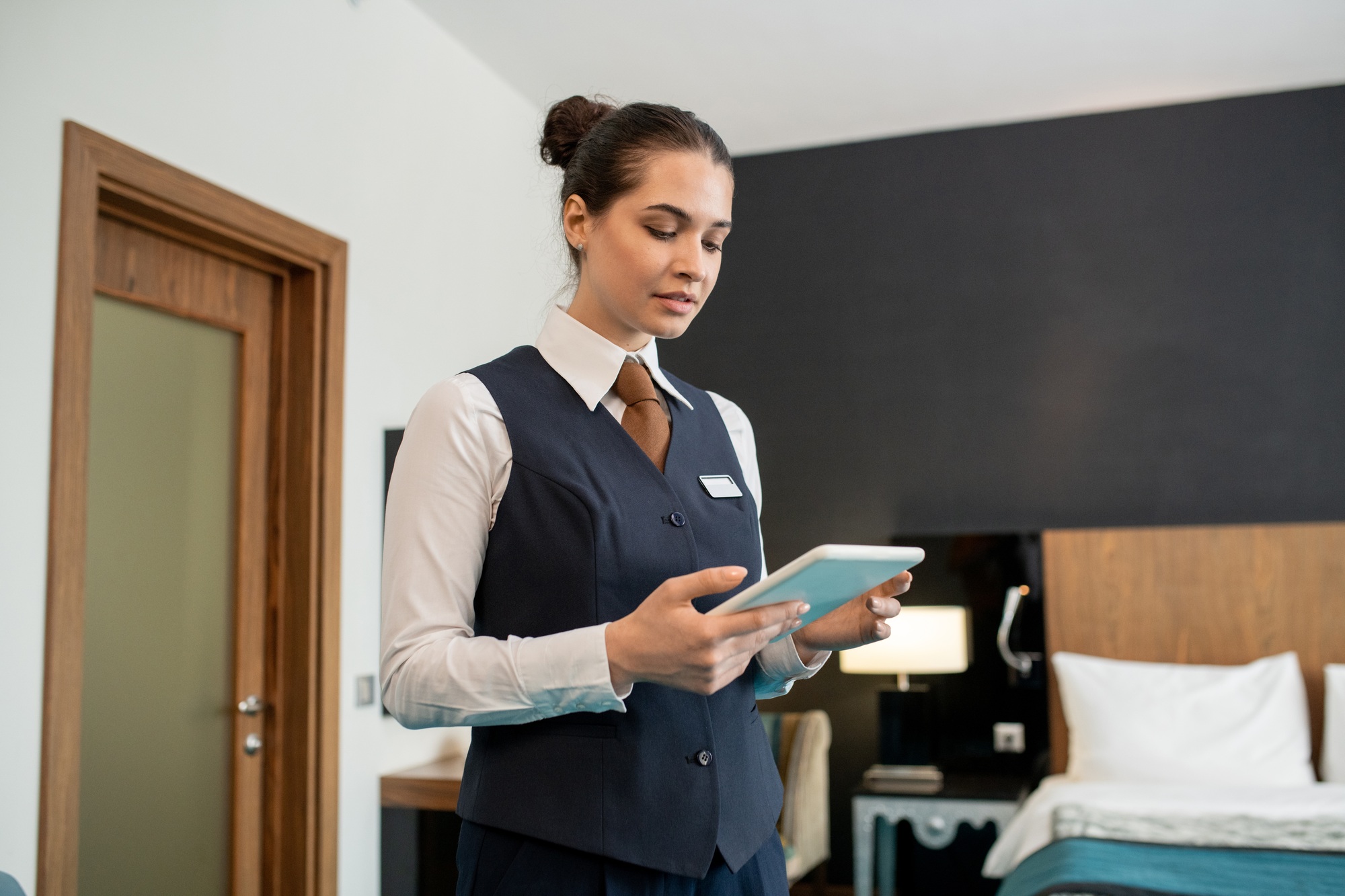 Young hotel worker using tablet in bedroom